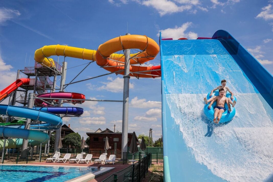 A water slide at a water park with two people on it.